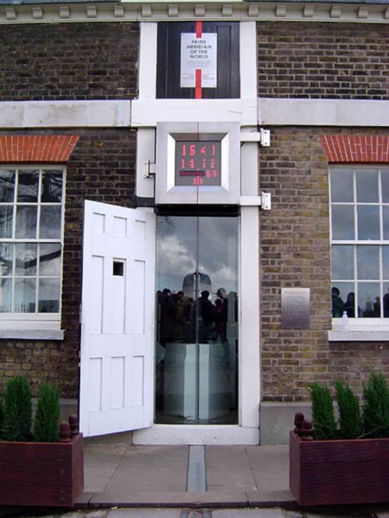 Photograph of the Royal Observatory at Greenwich England. There is an open doorway with a plaque over it, and a brass line embedded in the walk and steps leading up to the door, and above the door to the roof
