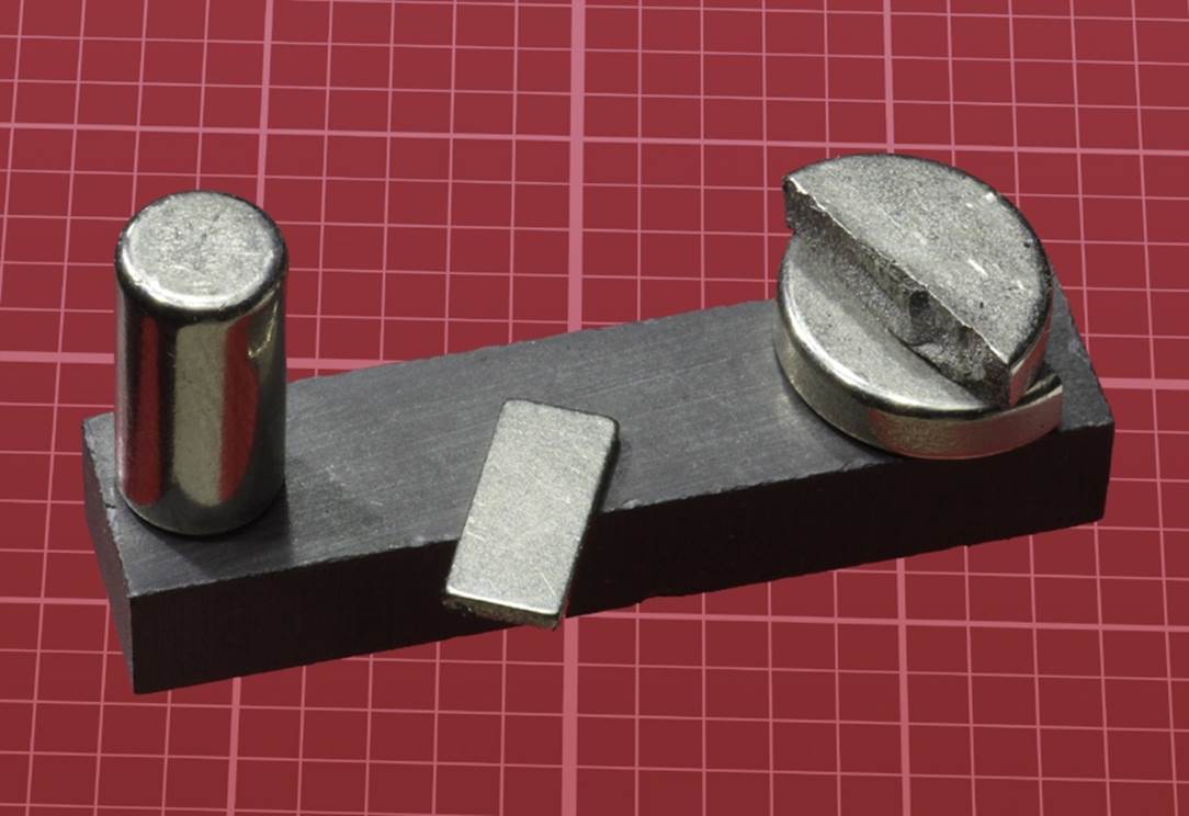 A selection of magnets (one of which broke when it was grabbed by another). The dull gray magnet is iron; the others are neodymium.